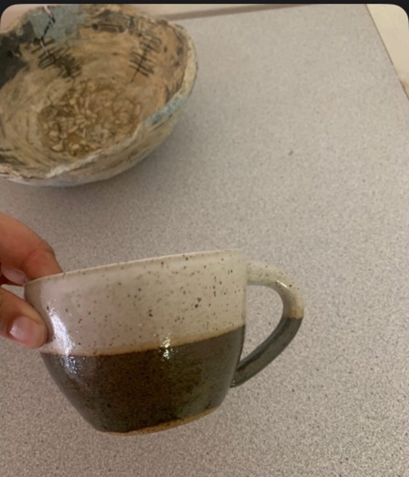 coastal blue + cream mug, held — speckled cream over dark brown