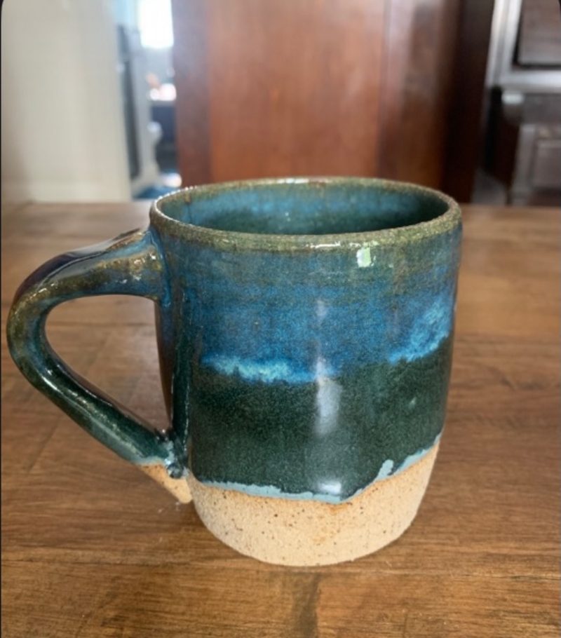 bluegreen mug on the table — bands of blue and green over a speckled foot