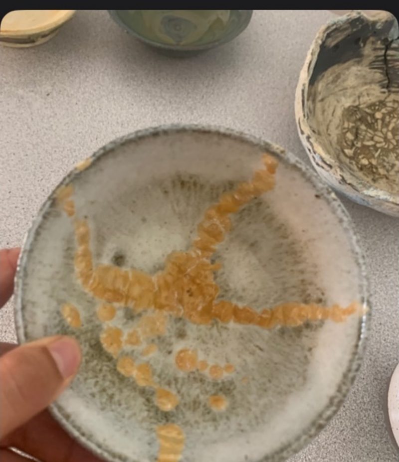 cream and gold — a shallow bowl held in one hand, cream glaze crackled with gold