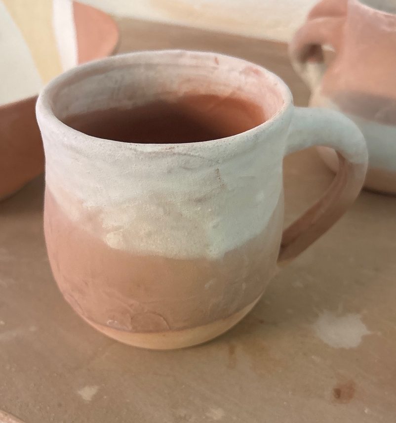 Cosmic mug, unfired — pale pink and white, on the shelf