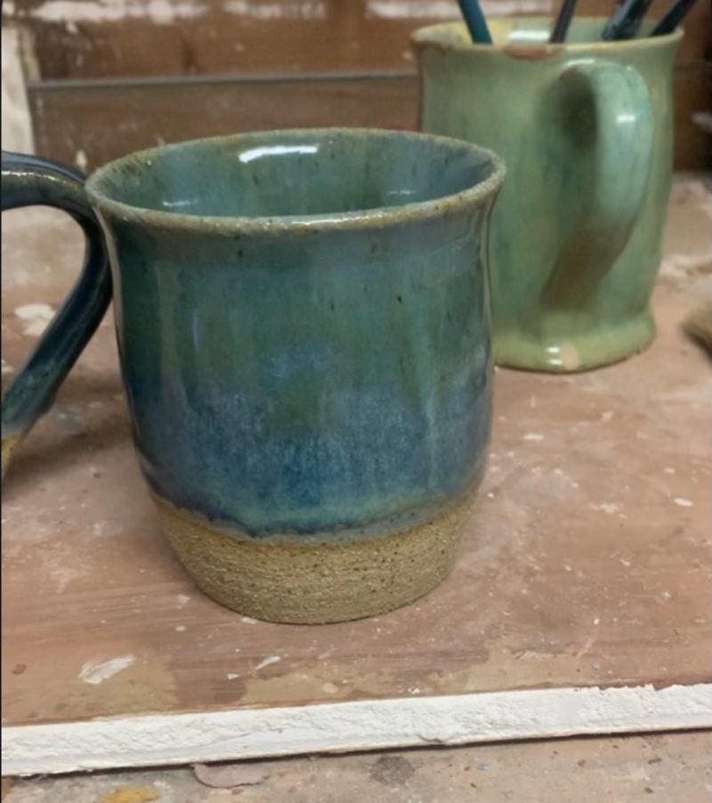 aqua with cream mug on the bench — teal glaze over a raw clay foot