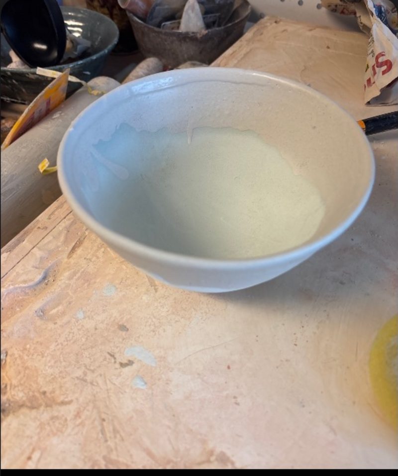 Smaller bowl — a pale bowl on the cluttered bench, glaze pooled thin